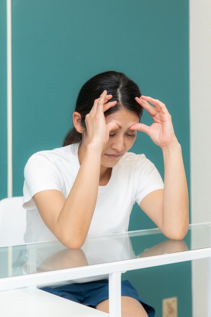こめかみを指で押さえる女性